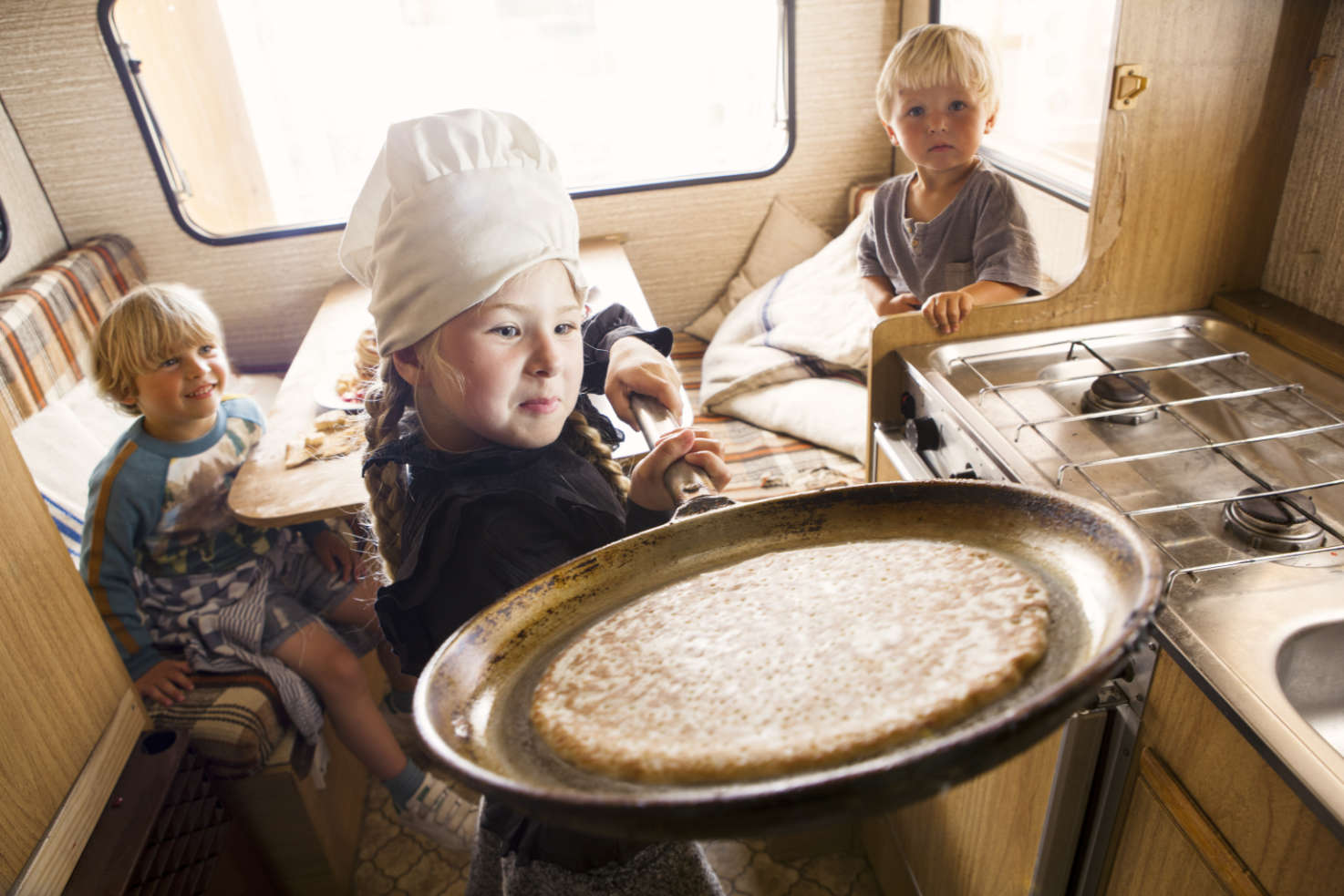 Drie kinderen spelen in een caravan