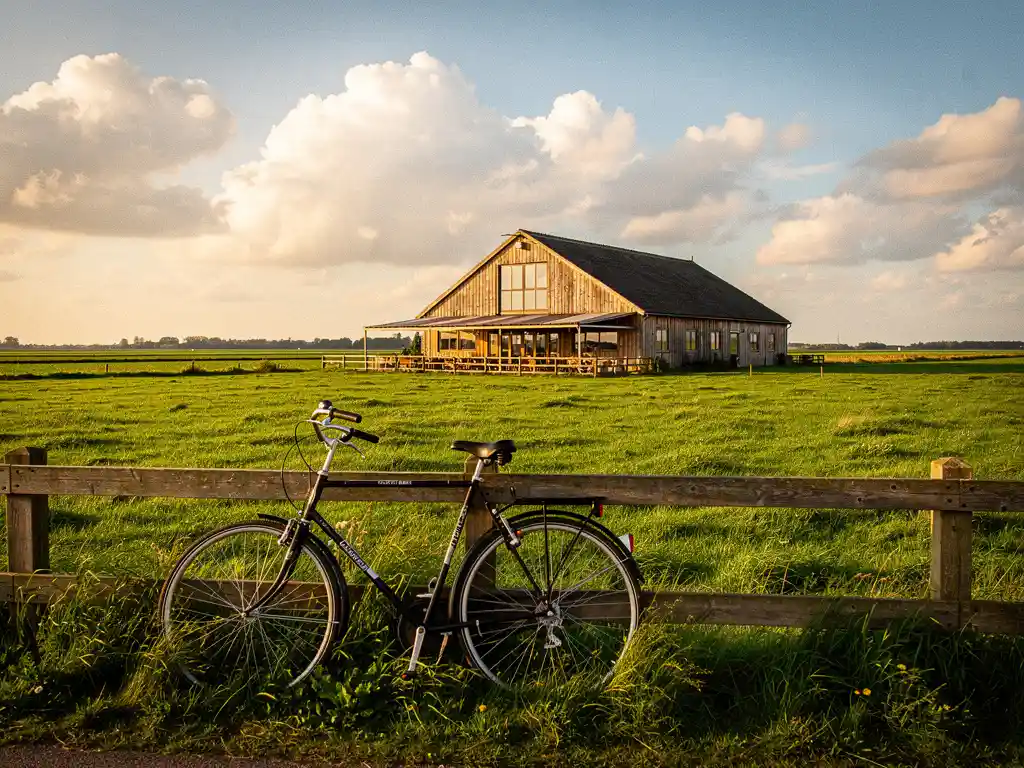 Fiets tegen houten hek op het Eiland van Schalkwijk, met groene polderweide, rustieke houten boerderijrestaurant en wolkenlucht boven Utrecht.
